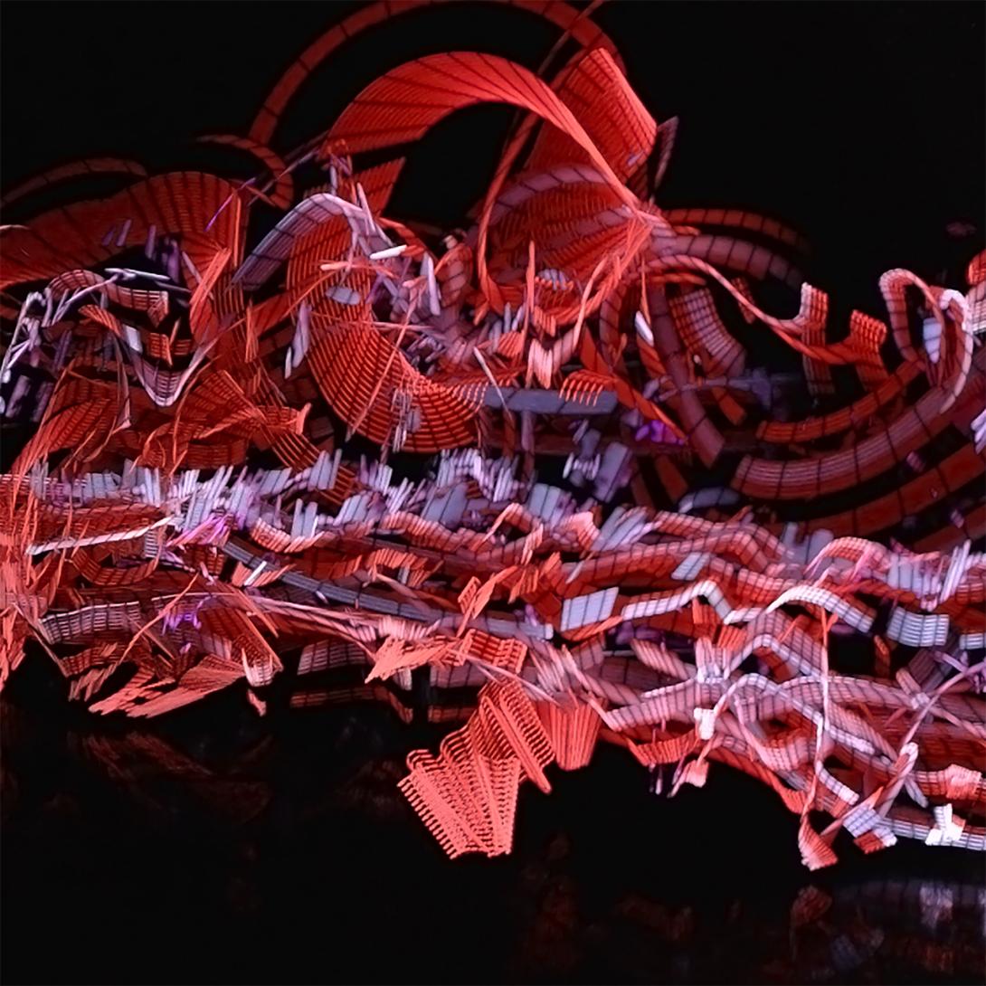 Image made by lightpainting. On a black background, there are various striped trails of red and blue hues, some sharp and some blurred.