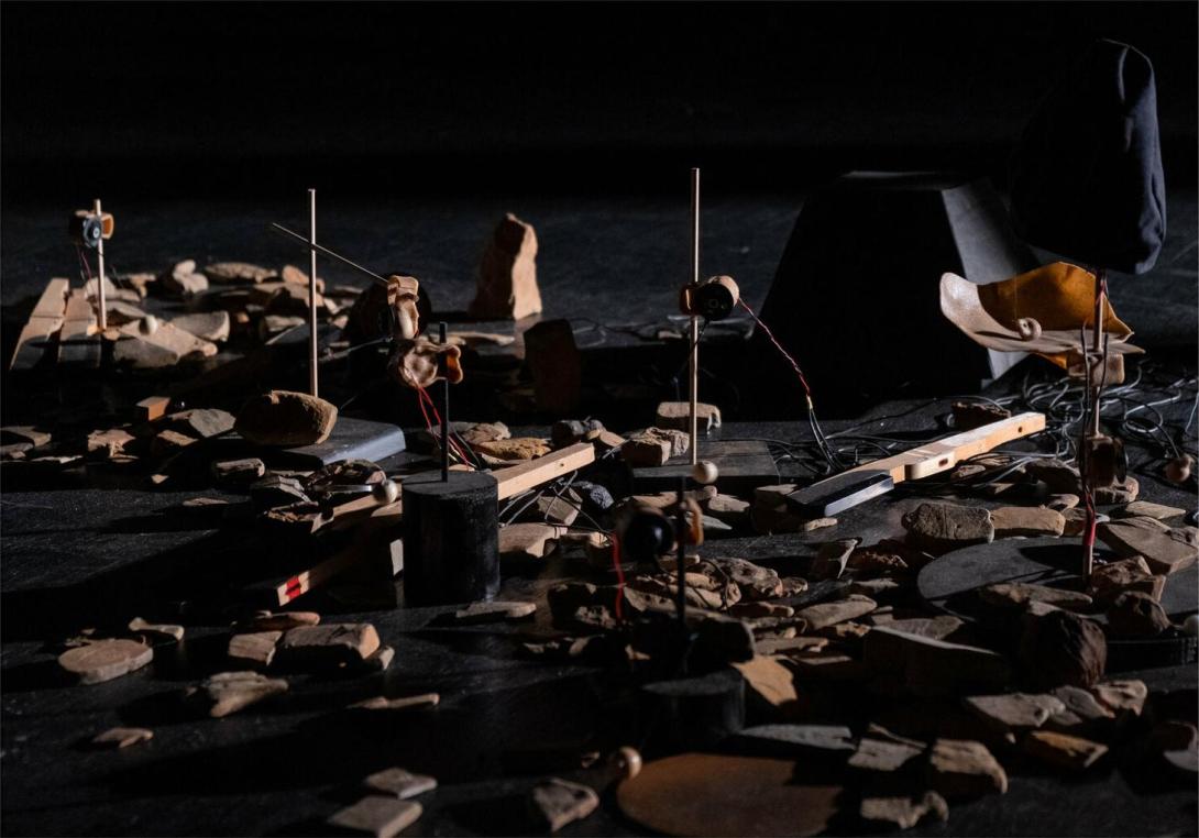 Still from 'Trust me tomorrow' showing a close up of the stage floor littered with rocks and detritus, many of which are connected to mechanical motors.