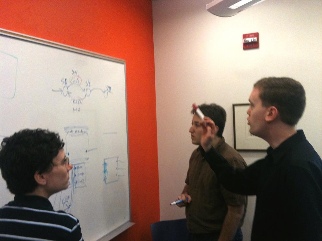 A photo of part of Team Vuo discussing an algorithm drawn on a markerboard